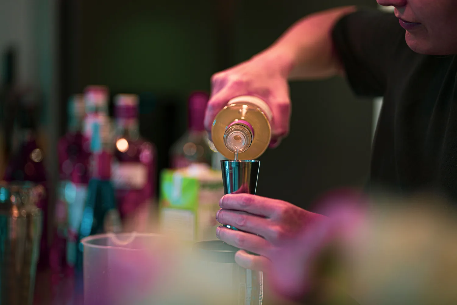 Bartender mixing cocktails behind a well stocked bar